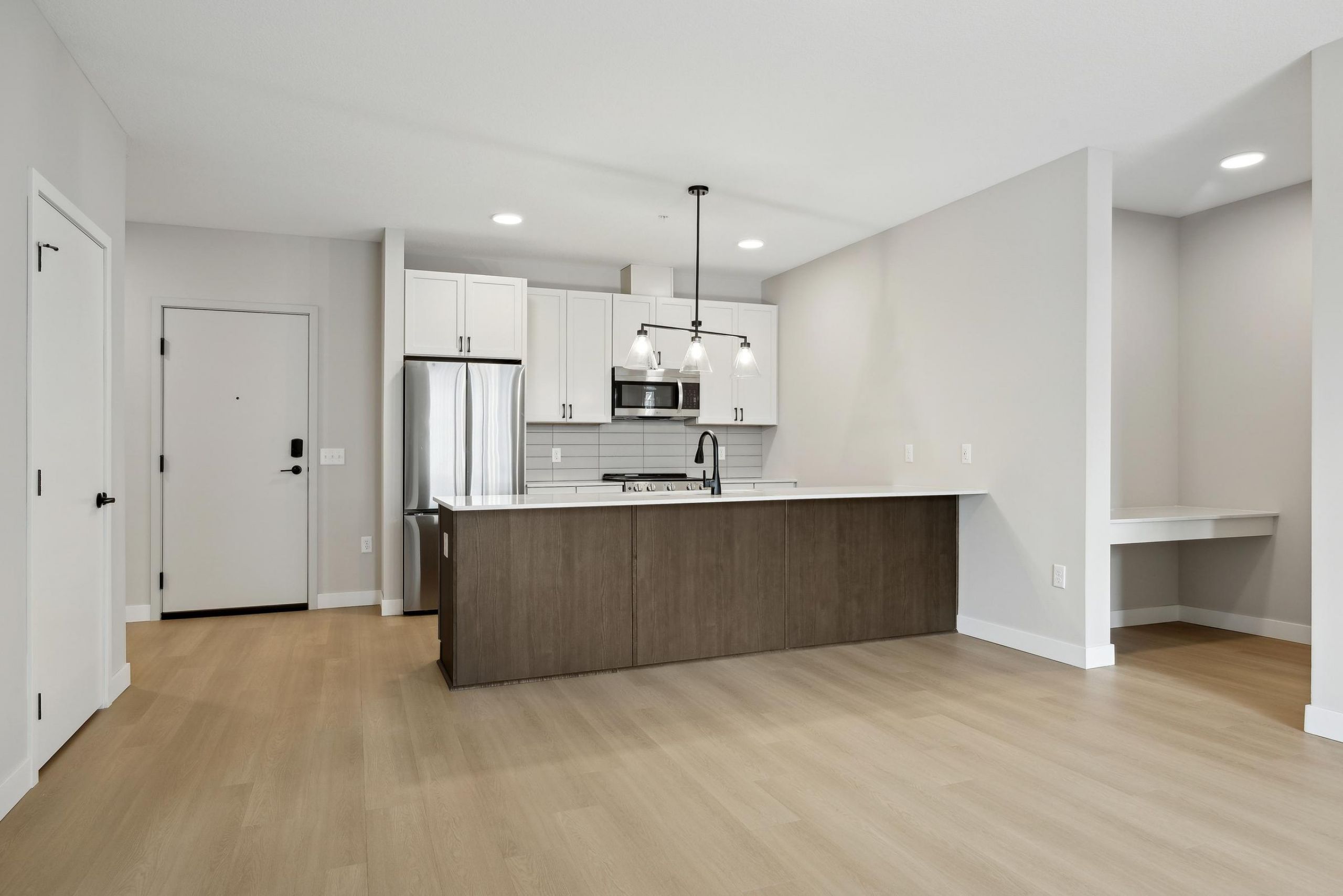 Modern kitchen with white cabinets, stainless steel appliances, and a large wooden island in an open space.