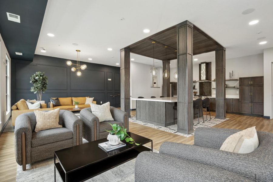 Modern living room with gray chairs, a yellow sofa, and a sleek kitchen area with pendant lighting.