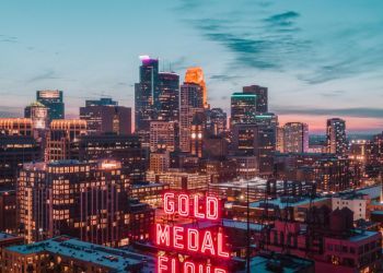 A neon "Gold Medal Flour" sign glows with a city skyline at dusk in the background.