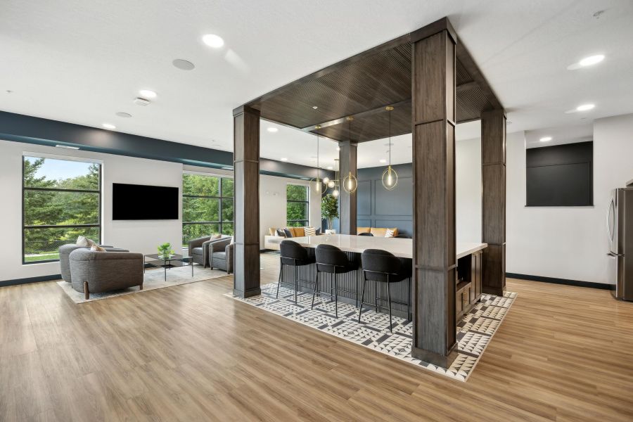Modern open-concept living space with large windows, seating area, and a kitchen island with bar stools.