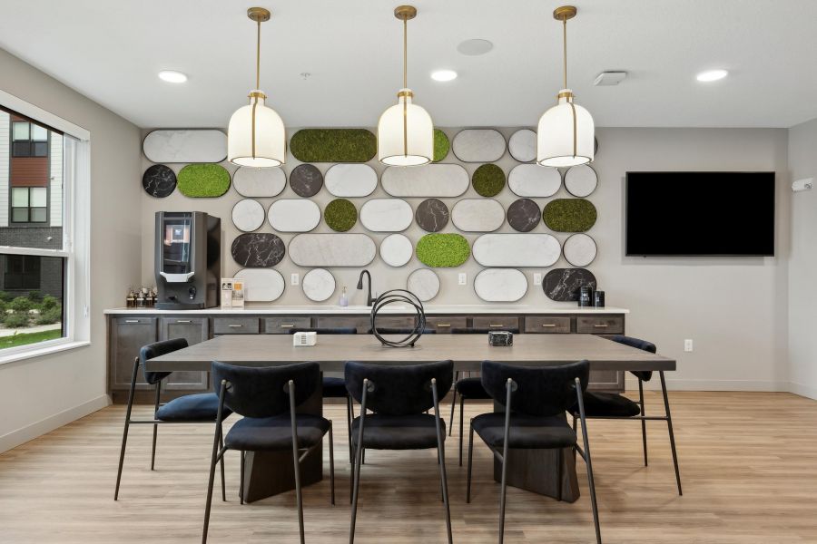 Modern dining area with dark chairs, pendant lights, and a geometric wall with green and white accents.